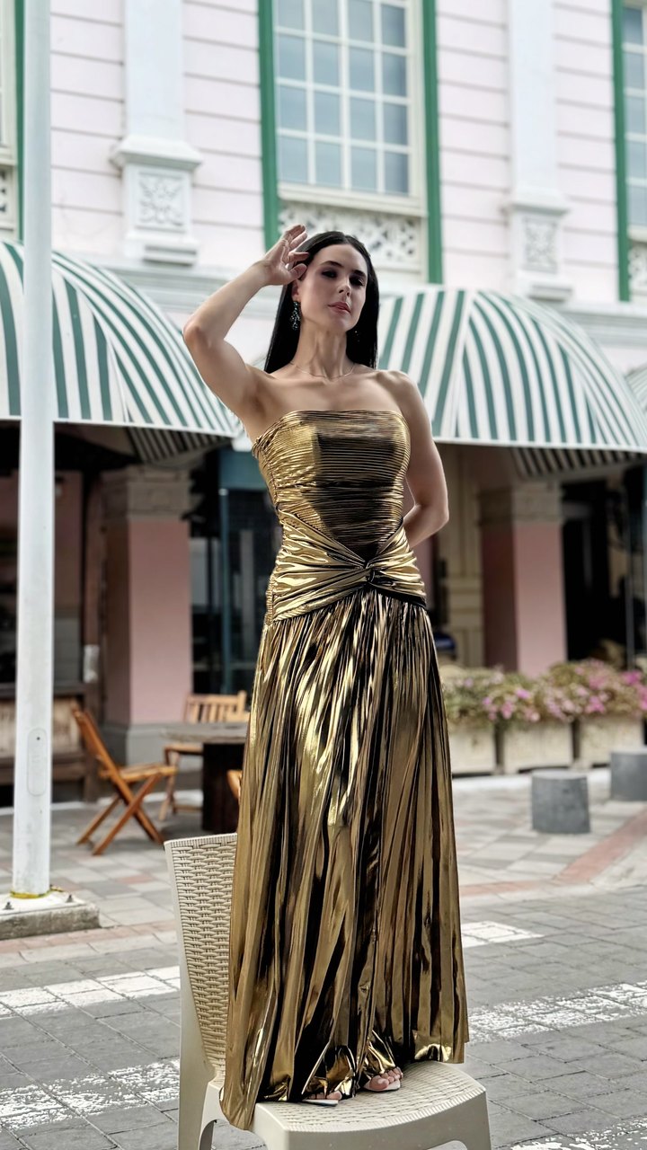 Modelo con vestido largo dorado plisado