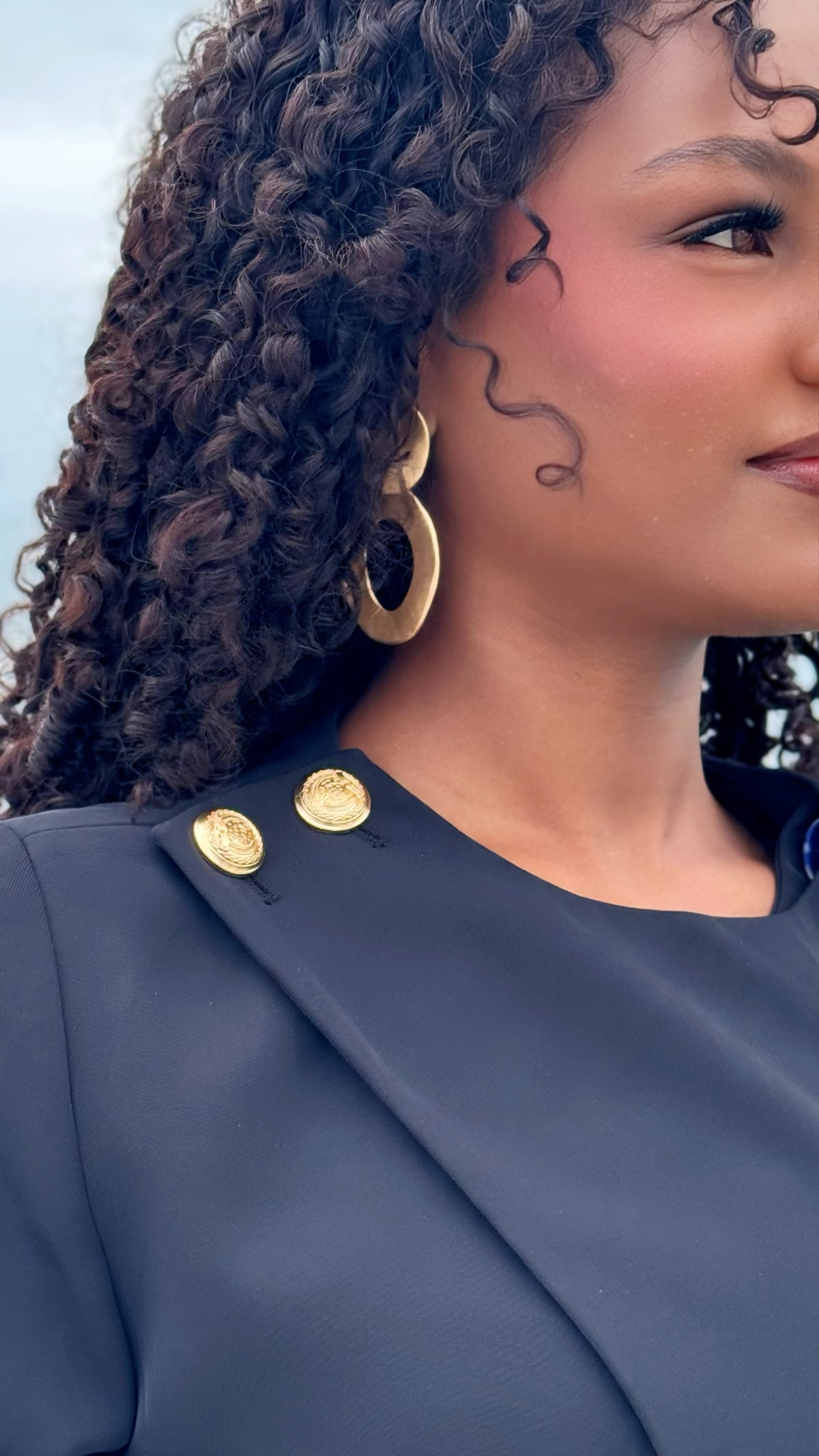 Modelo con blazer negro Exotica de corte cruzado y botones dorados, estilo formal y elegante para mujer.